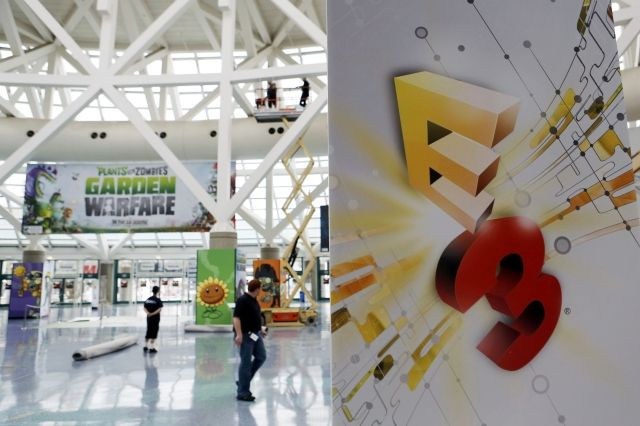 Workers set up signage and exhibits at the main registration entrance of E3 2013 in Los Angeles, California
