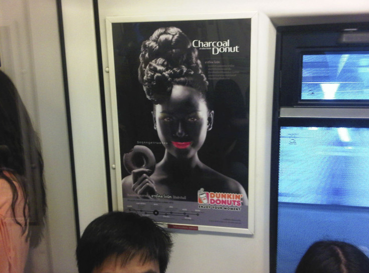 An advertisement poster of a smiling woman with bright pink lips in blackface makeup holding a doughnut is seen on a Skytrain, a commuter train in Bangkok, Thailand.
