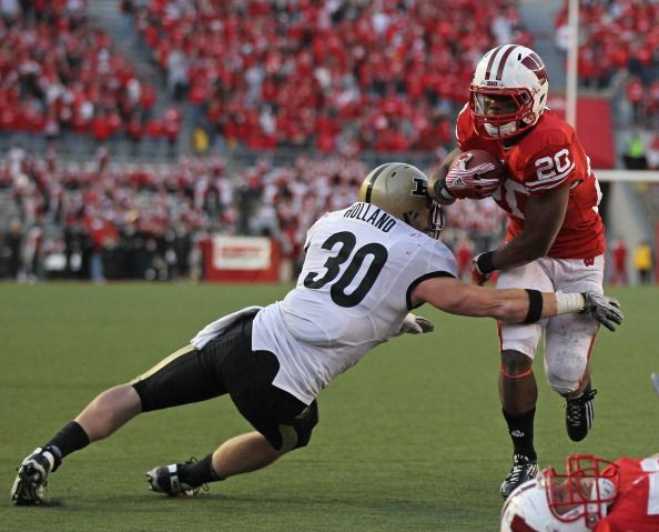 James White #20 of the Wisconsin Badgers breaks away from Joe Holland #30 of the Purdue Boilermakers on a touchdown run at Camp Randall Stadium on November 5, 2011 in Madison Wisconsin. Wisconsin defeated Purdue 62-17.