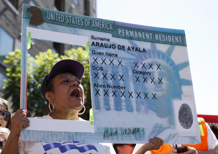 A woman holds up a replica green card sign in Hollywood, Los Angeles.