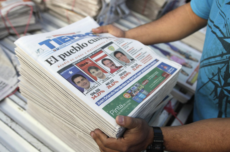 A vendor arranges newspapers covering the preliminary tally of presidential candidates on the front page, in Tegucigalpa November 25, 2013
