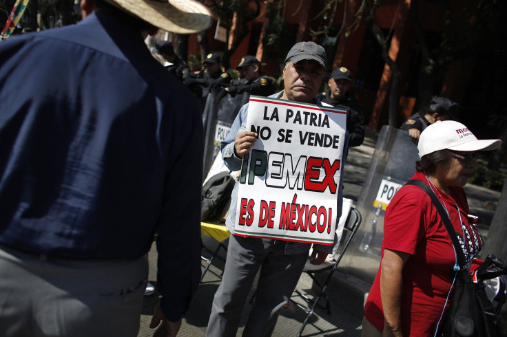 A demonstrator holds a placard that reads 'Homeland is not for sale, Pemex is for Mexico' during a protest against the energy reform bill outside the Senate building in Mexico City December 6, 2013.