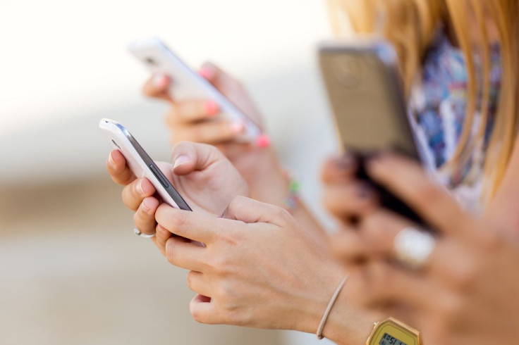 shutterstock_22047894Three girls chatting with their smartphones at the park7