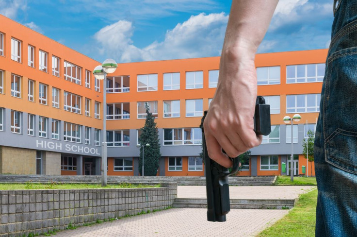 Gun control concept. Young armed man holds pistol in hand in public place near high school. 