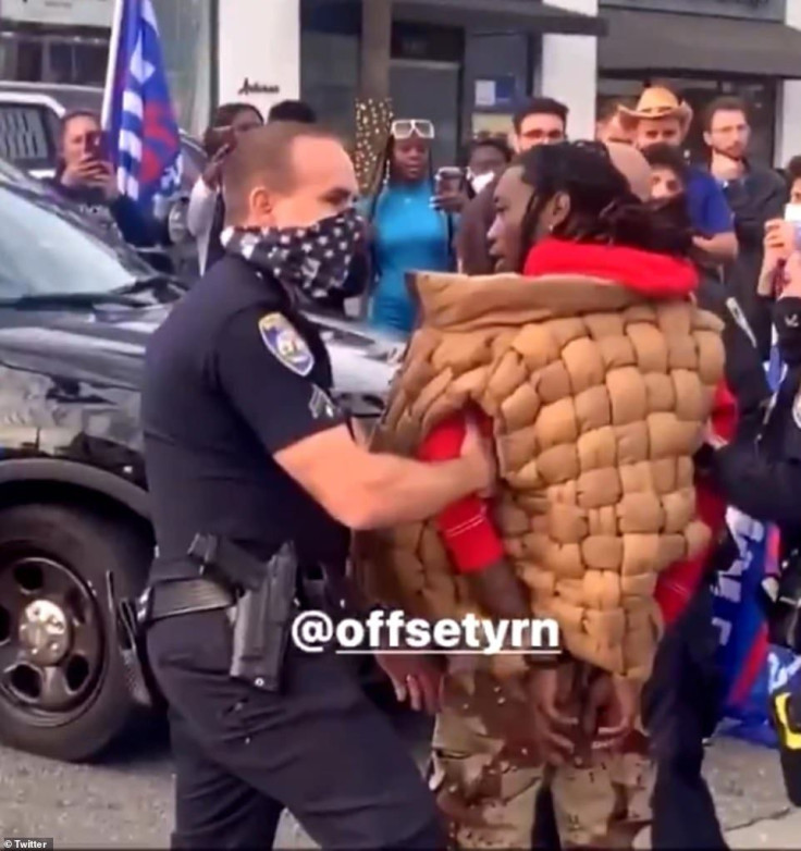 A clip shared by an onlooker shows the musician in handcuffs amid a crowd of Trump supporters. 