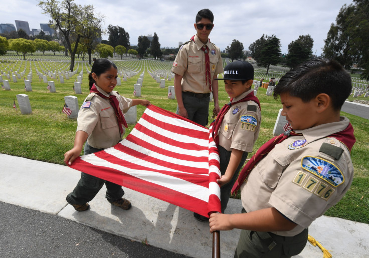 Boy Scouts from the Long Beach troop prepare a US flag besides the graves of war veterans during the annual 'Flag Placement ceremony' to honor the fallen for Memorial Day at the Los Angeles National Cemetery, California