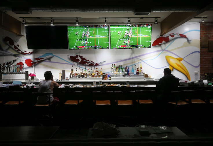 Restaurant workers sit during a break as Super Bowl LV plays on television