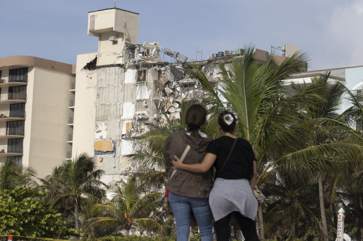 Maria Fernanda Martinez and Mariana Cordeiro (L-R) look on as search and rescue operations continue at the site of the partially collapsed 12-story Champlain Towers South condo building on June 25, 2021 in Surfside, Florida.