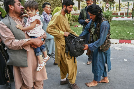 A Taliban fighter searches the bags of people coming out of the Kabul airport in Kabul 