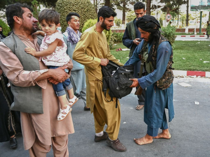 A Taliban fighter searches the bags of people coming out of the Kabul airport in Kabul