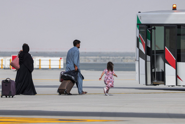 A girl runs towards an airport shuttle bus as people disembark off a Royal Air Force military transport aircraft