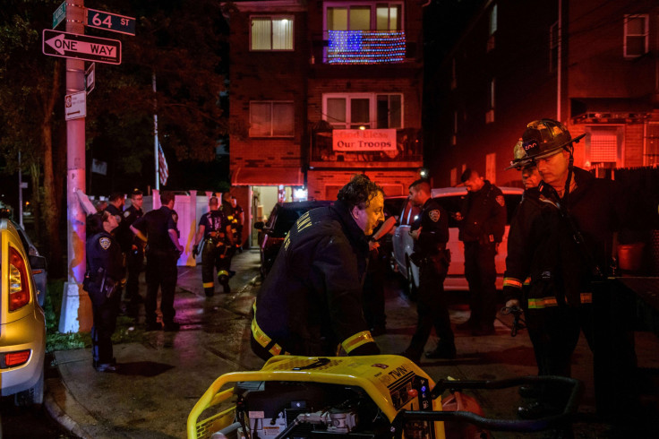 Police officers and rescue workers gather outside a house where a person was trapped in a flooded basement in Queens, New York 