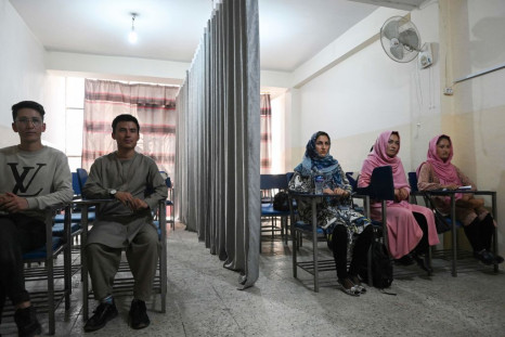 Students attend a class bifurcated by a curtain separating males and females at a private university in Kabul
