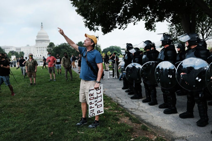 Police in riot gear stand in front of the U.S. Capitol