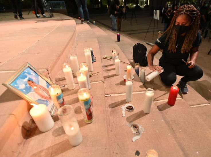 Actor Sarah Wilkinson lights a candle around a photo of cinematographer Halyna Hutchins