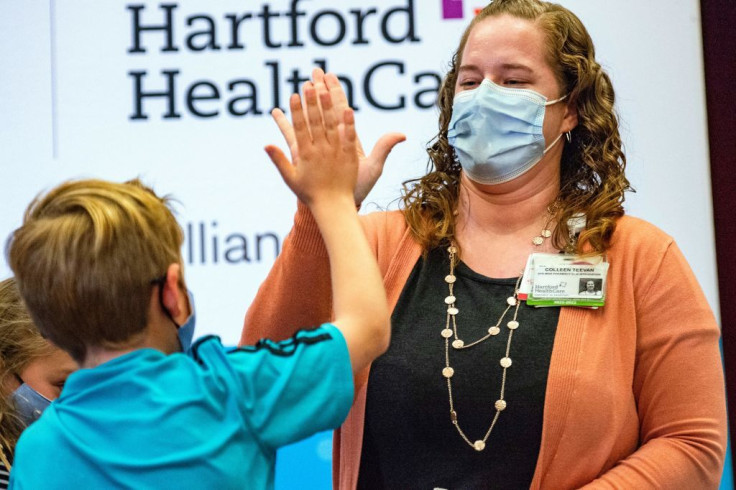 A ten year old child high fives Pharmacist Colleen Teevan after he received the Pfizer-BioNTech Covid-19 Vaccine for kids