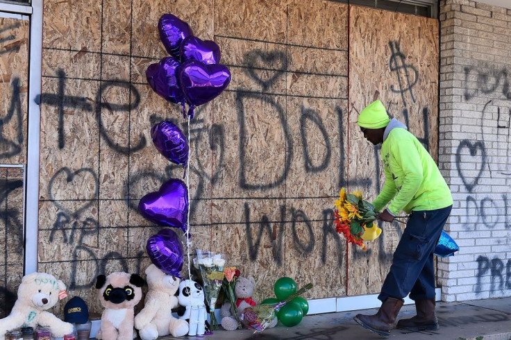 A man places flowers at the memorial for Young Dolph outside of Makeda's Cookies bakery