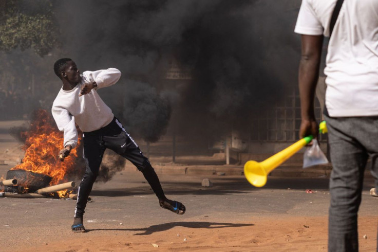 A protestor throw rocks in reaction to police's firing tear gas during a demonstration in Ouagadougou