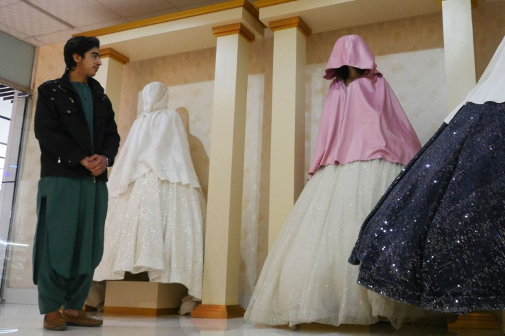 A shopkeeper (L) stands next to mannequins with the heads covered