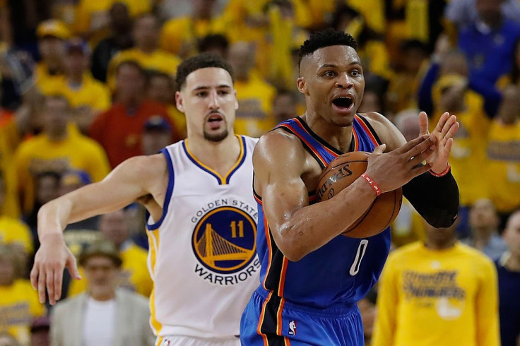 Russell Westbrook #0 of the Oklahoma City Thunder attempts to call for a time out ahead of Klay Thompson #11 of the Golden State Warriors