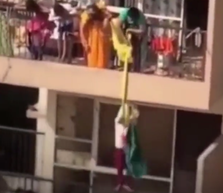 Mother dangles son from high rise building to fetch fallen saree.