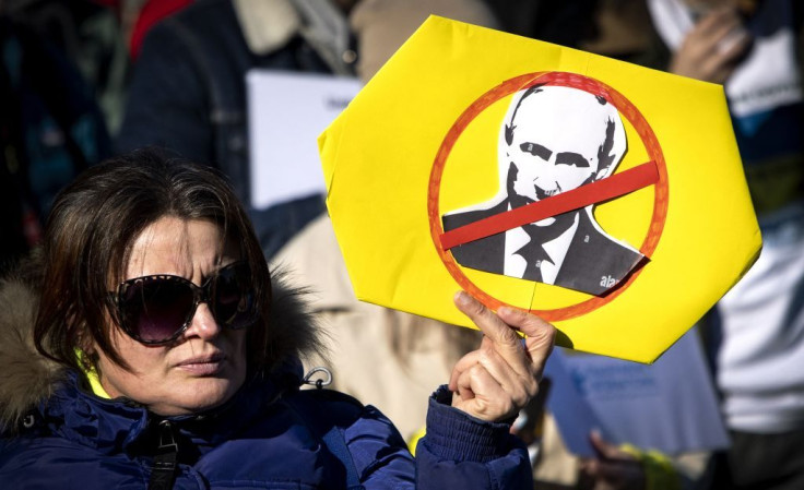 A woman holds a placard depicting Russian President Vladimir Putin