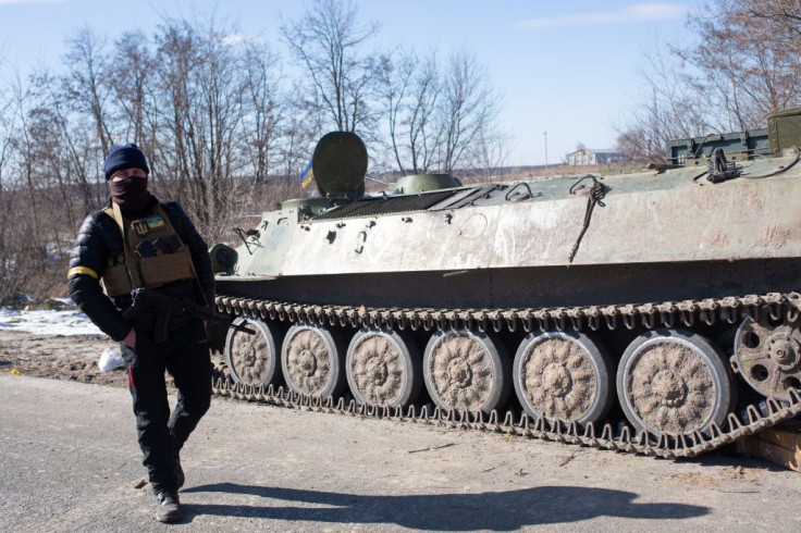 Ukrainian serviceman walks by a Russian armored personnel carrier