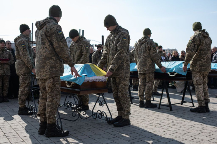 Ukrainian servicemen place Ukrainian flags over the coffins during the funeral service for Oleh Yaschyshyn, Sergiy Melnyk, Rostyslav Romanchuk and Kyrylo Vyshyvany in Lychakivske cemetery on March 15, 2022 in Lviv, Ukraine.