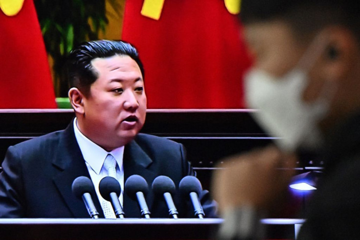 A man walks past a television report showing a news broadcast with file footage of North Korean leader Kim Jong Un