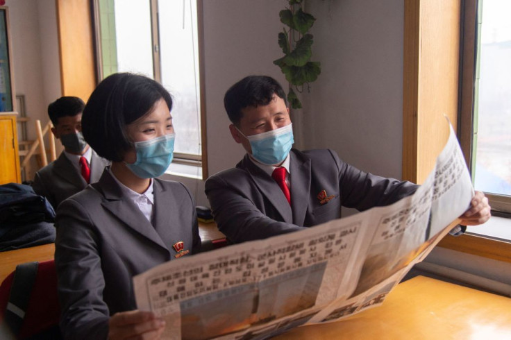Students of the Pyongyang Jang Chol Gu University of Commerce look at the Rodong Sinmun newspaper 