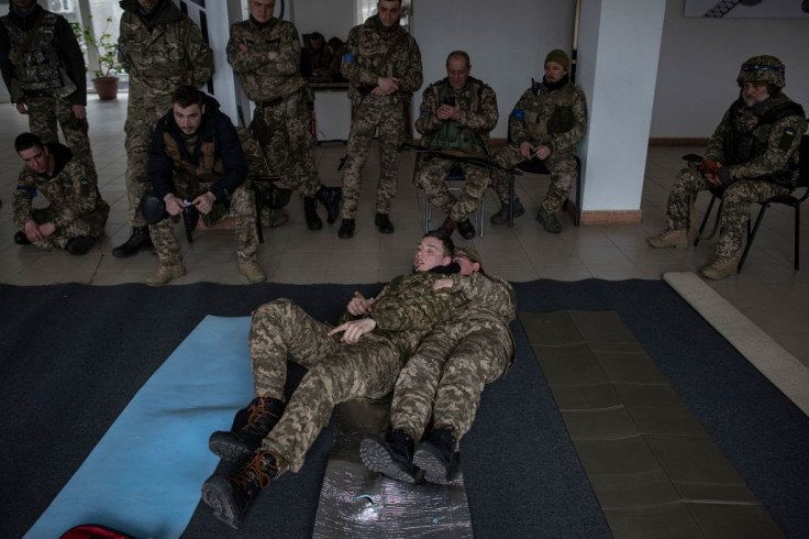 A first aid training instructor shows how to drag a soldier from the battlefield during a first aid training