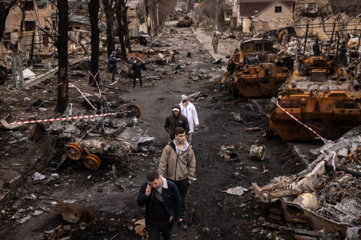 People walk through debris and destroyed Russian military vehicles