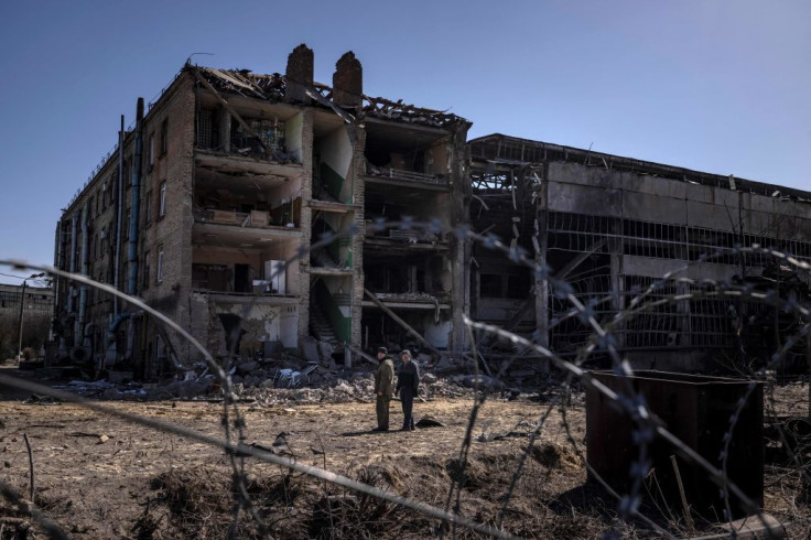 People stand beside damaged buildings at the Vizar company military-industrial complex, after the site was hit by overnight Russian strikes, in the town of Vyshneve, southwestern suburbs of Kyiv, on April 15, 2022. 