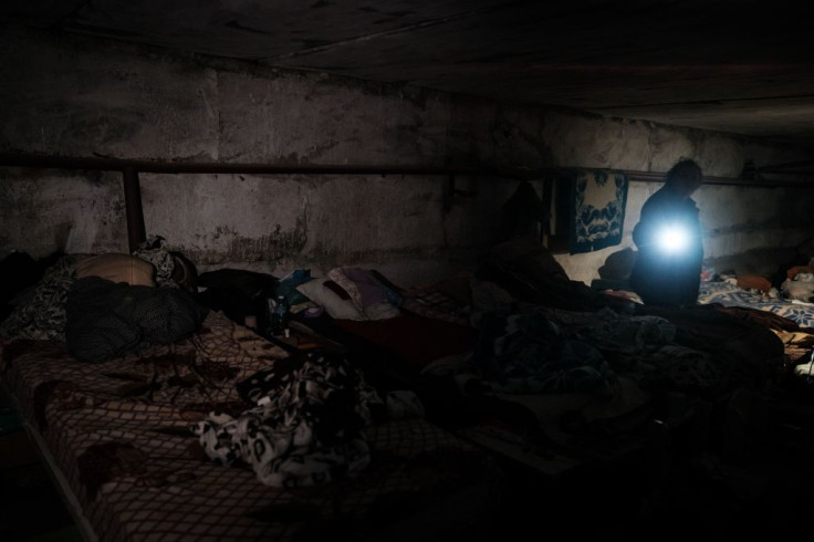 Natalia Georgiyevna, 70, uses a torch as she stands in the makeshift shelter of a kindergarten's basement, where she has been living with other six people for more than two months, in Lysychansk, eastern Ukraine