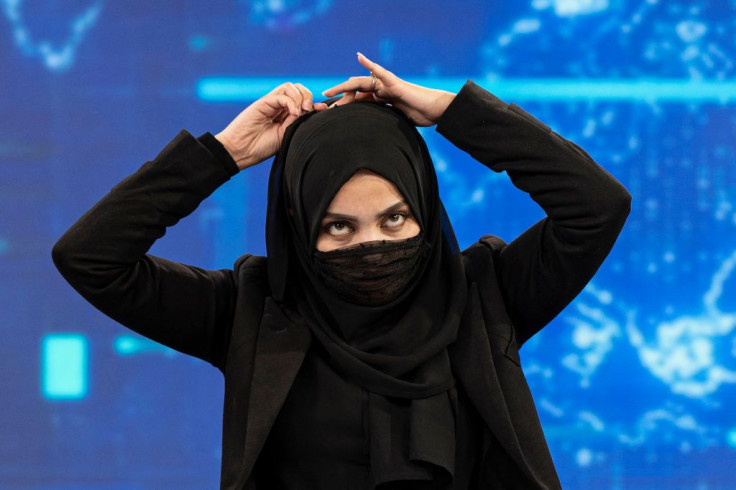 A female presenter for TOLOnews, Thamina Usmani, covers her face during a live broadcast