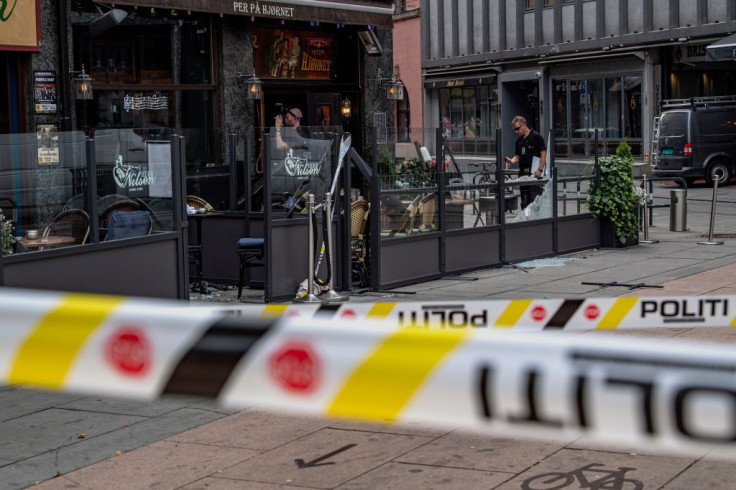 Police examine the restaurant whose windows were shattered by a mass shooting in Oslo