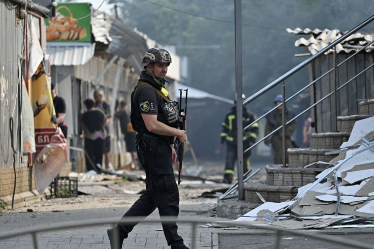 A Ukrainian policeman patrols in front of destroyed shops on a local market
