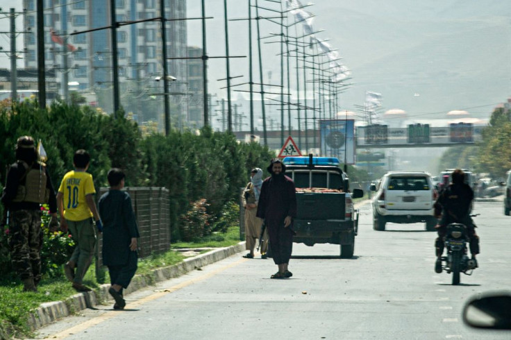 Taliban fighters (C) stand guard along a road near the Russian embassy after a suicide attack in Kabul