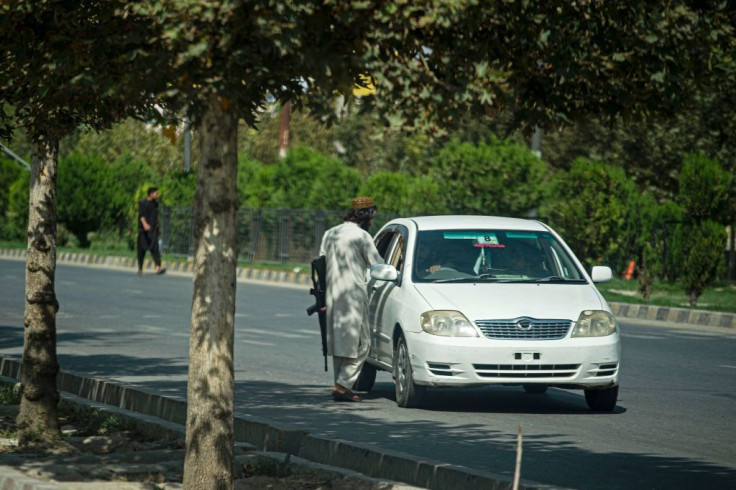 A Taliban fighter speaks with the driver of a car near the Russian embassy after a suicide attack in Kabul
