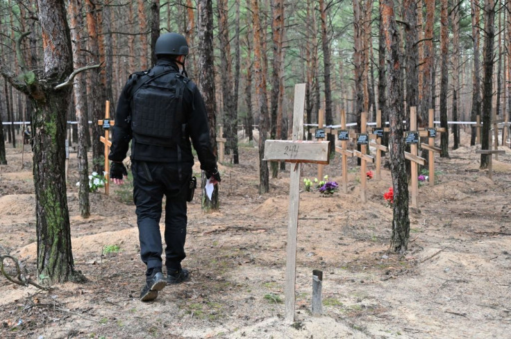 A Ukrainian police officer walks at a burial site in a forest on the outskirts of Izyum, eastern Ukraine on September 16, 2022. 