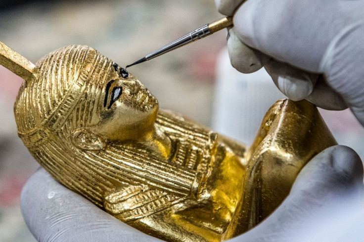 A technician paints a replica of an Ancient Egyptian statue
