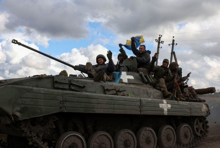 Ukrainian soldiers wave a national flag as they ride on a personnel armoured carrier on a road near Lyman