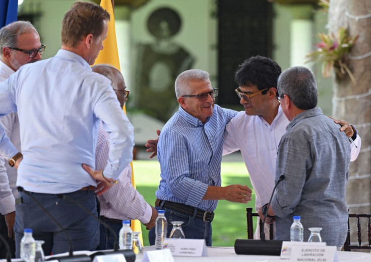 The Colombian Government's Commissioner for Peace, Danilo Rueda (C) hugs commanders of ELN