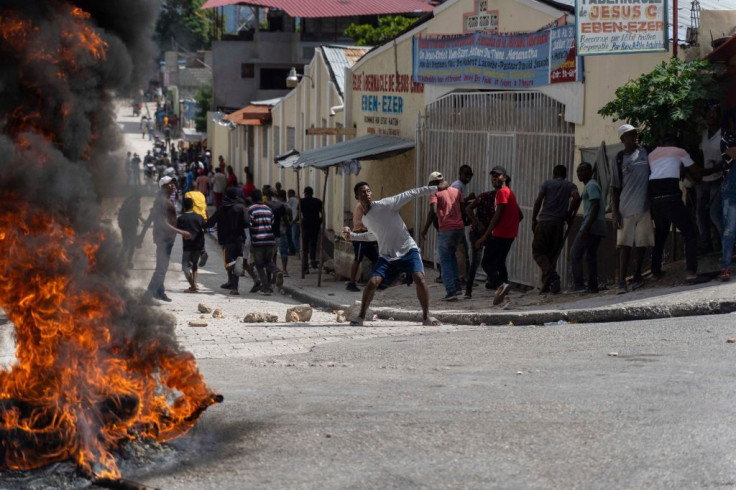 A man holds a stone as protesters demand the release of Haitian journalist Robest Dimanche