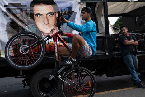 A young man performs a stunt while activists of the "Free Alex Saab" get ready for a movement 