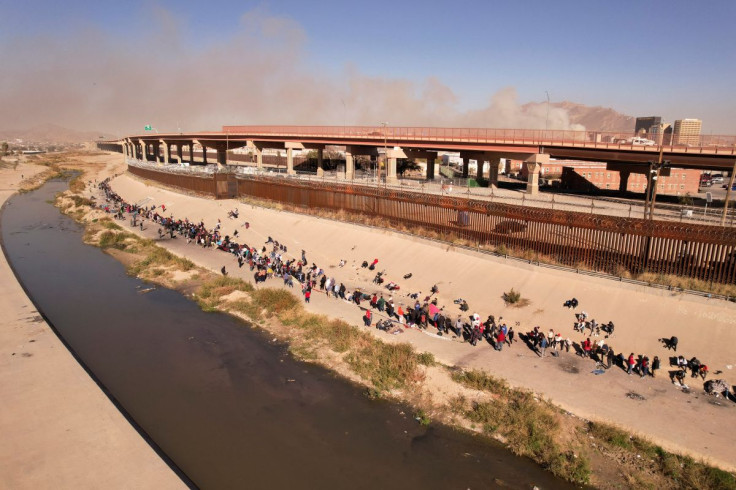 Migrants queue near the border wall