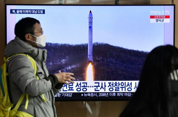 A man walks past a television screen showing a news broadcast with file footage of a North Korean missile test