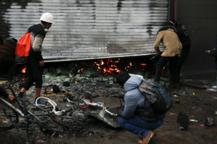 Supermarket workers inspect fire damage after street clashes in Puno, Peru