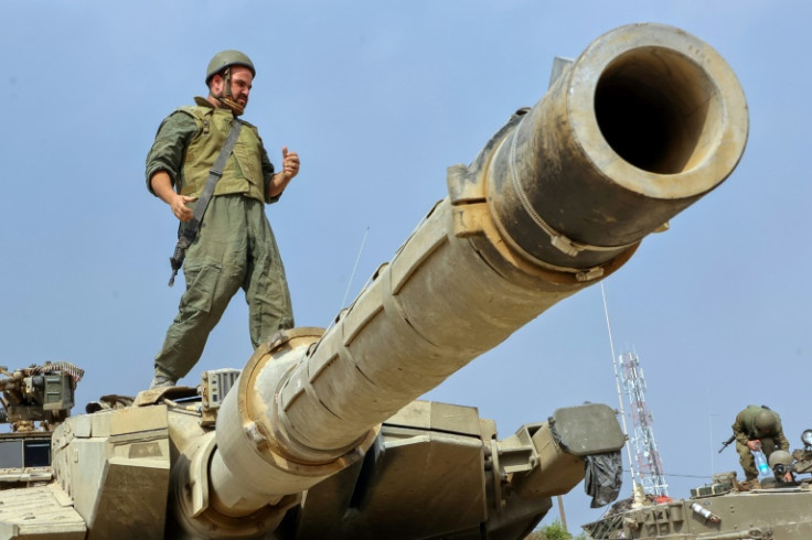 An Israeli soldier stands on the turret of a tank. 