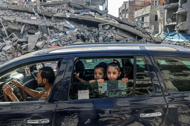 Palestinians drive amid the rubble of buildings